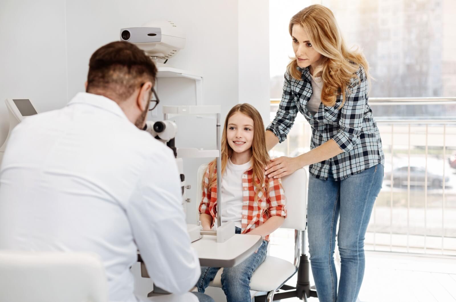 An eye doctor discussing eye exam results with a child and their parent.