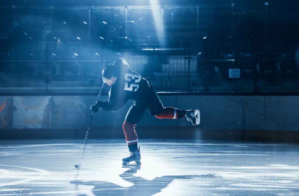 Athlete in hockey gear taking a shot during a game on an ice rink.