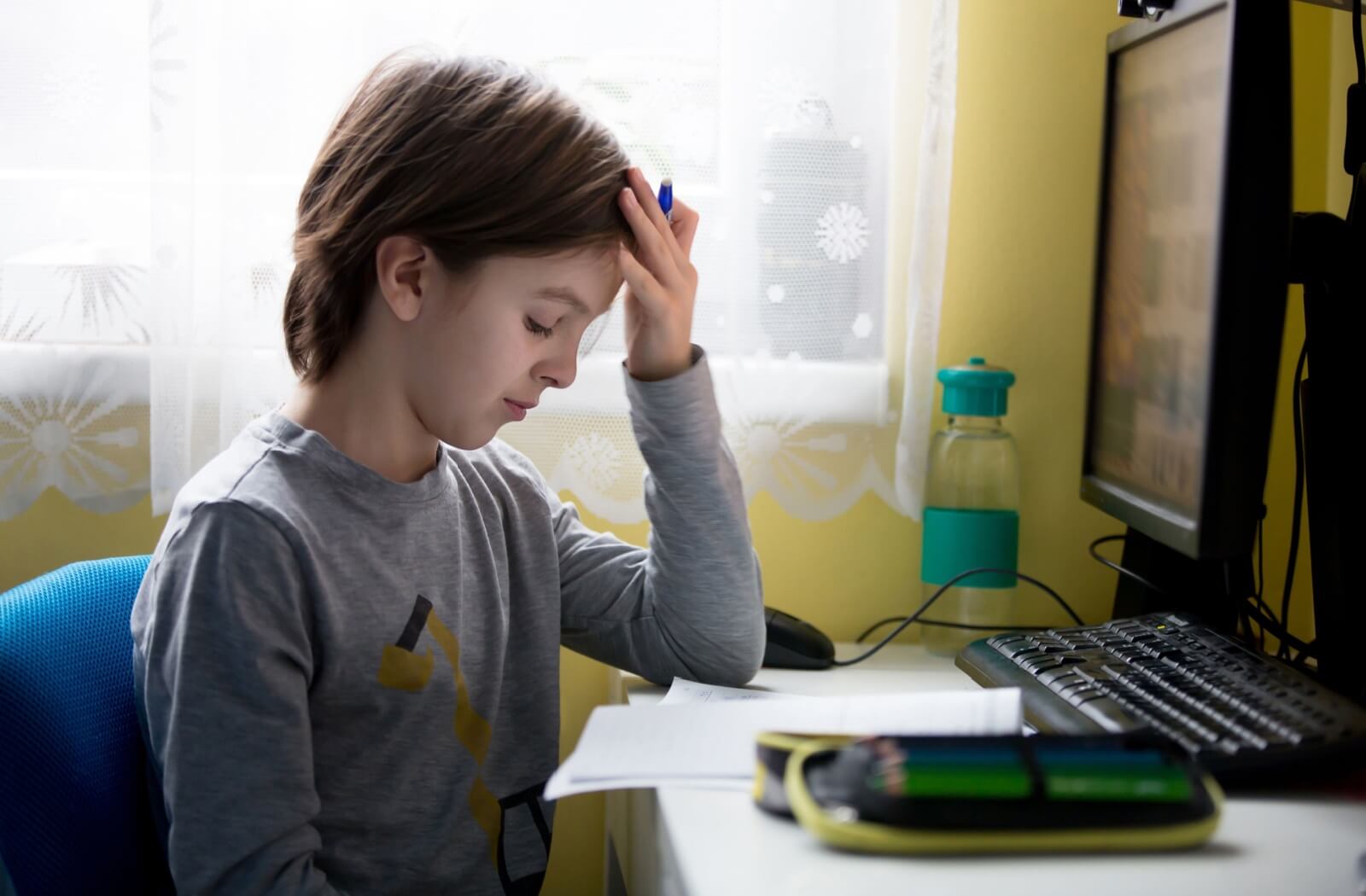 A child struggling with their homework that's jumping back and forth between computer and paper.