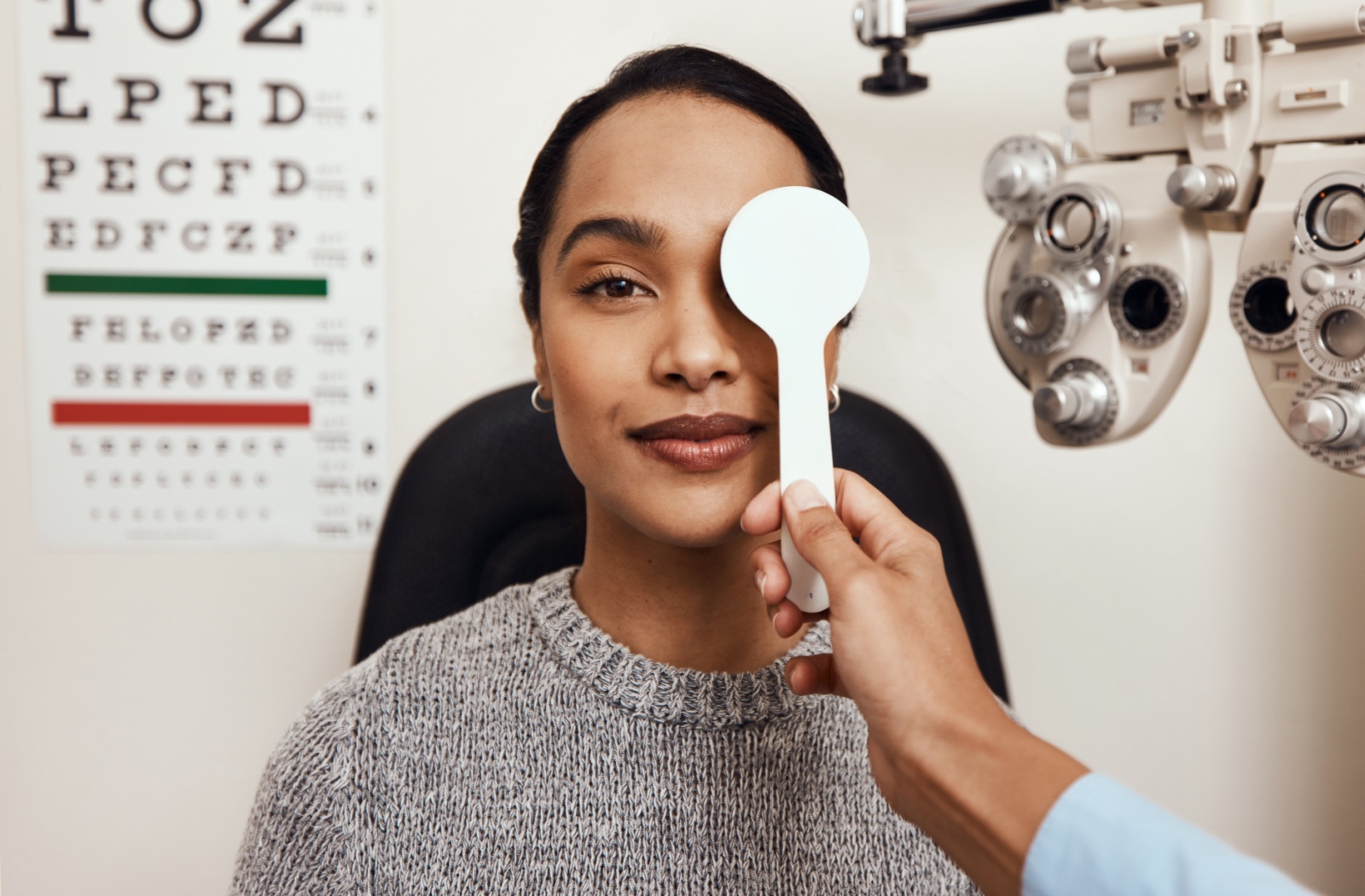 Optometrist covering one eye during vision test for amblyopia diagnosis.